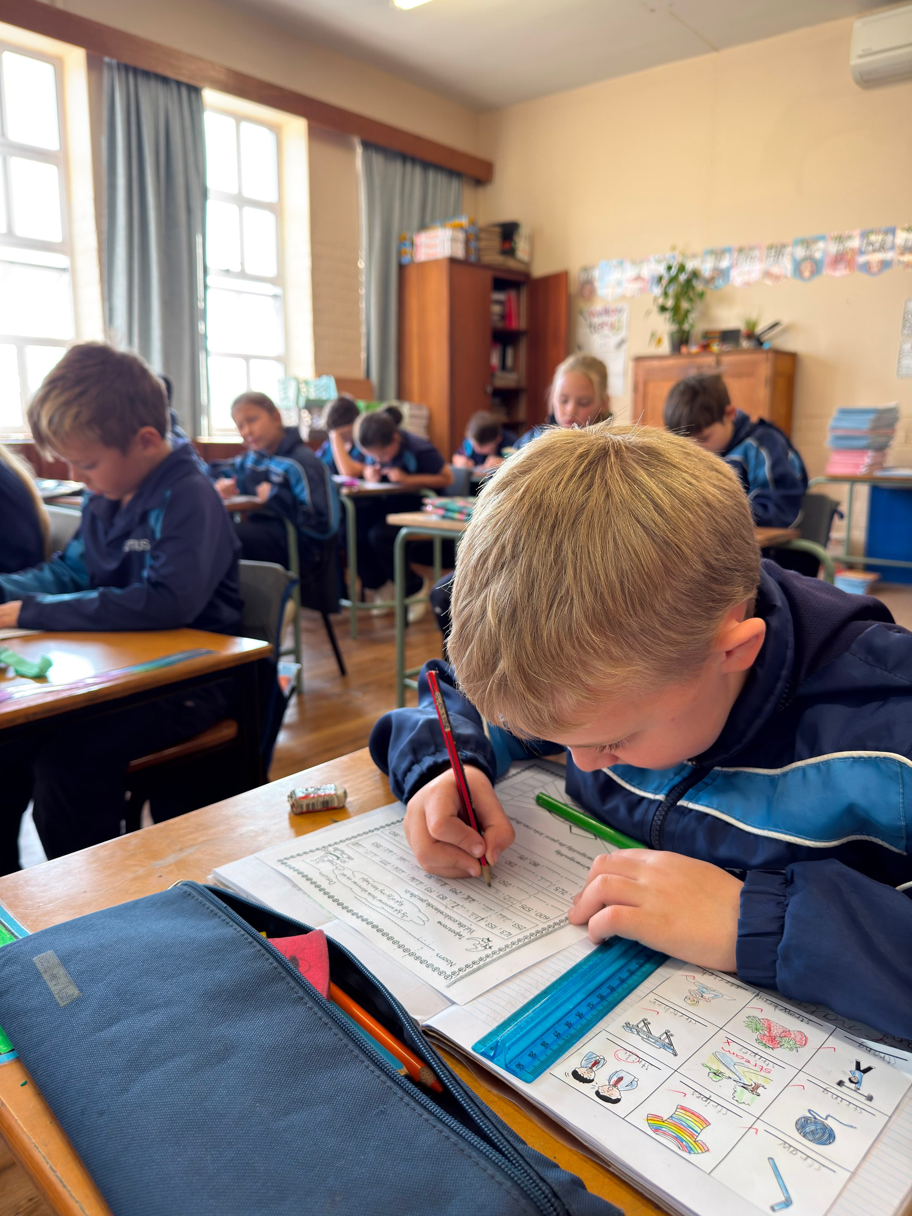 Jong leerder voltooi sy klaswerk